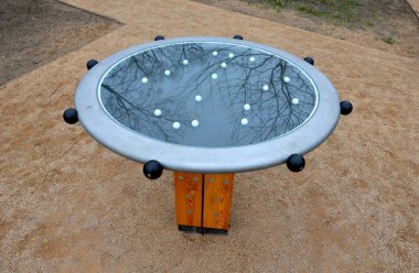 Tahta bir direğe sıkışmış metal bir disk. Toplarla açık hava oyun unsuru. İki çocuk topu deliğe sokmak için diski eğiyor..