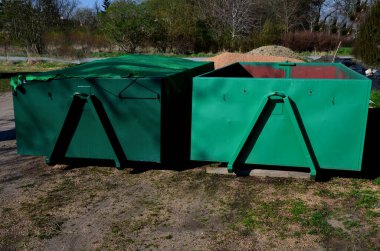 on the lawn is a green tin container for grass clippings from gardens and parks. a man checks the quality and quantity of grass by hand. a handful of green biological matter in the recycling compost