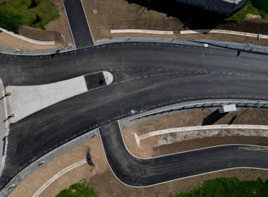 Yeni inşa edilmiş bir yol, üst üste dizilmiş perdeli ve asfalt halı katmanlarını görebilirsiniz. Çevresindeki alan beton oluğu olan bir hendeğe saplanmış. yağmur suyu drenajı