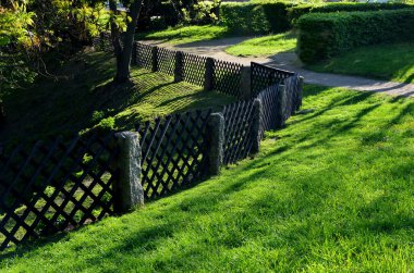 Eski moda bahçe çitleri. Taş ocağından direk olarak mort olan taş direkleri, aralarına çapraz kafes işi olan ahşap bir çit yerleştiriliyor.