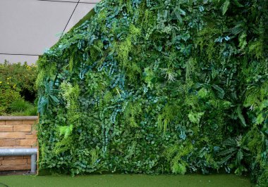 Otel lobisindeki yeşil bitki örtüsü sütunları, ofisler. Işık halojenleri fotosentez yapmak için bitkilerin üzerinde parlıyor. Sulama pompaları ve hortumların karmaşık sistemi plastik çiçeklerle değiştirilebilir