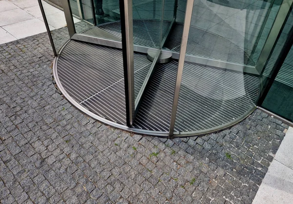 entrance revolving door with built-in mat. stainless steel frame. mechanical carousel that person entering must push. Aesthetic all-glazed four-leaf door. reducing energy leakage through air, sensor
