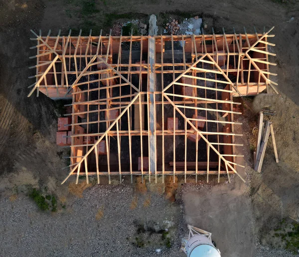 stock image view of the construction site of a family semi-detached house. silo with plaster cement mixture. Gable roof truss. beams are place, pallets of insulating bricks inside building, development, finance