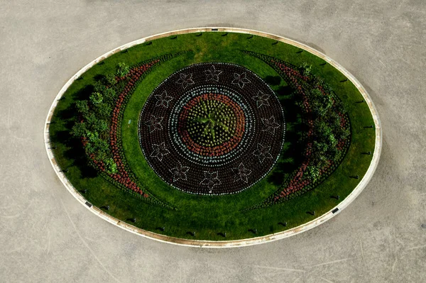ornamental flowerbed in front of the castle on the ground floor. The planting of annuals is in the shape of a circle with a moon shape. tree roses, stars, c moon, beige threshing sand