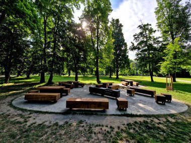 Tahta, büyük park bankının şekil bloğu granit doğal kaldırım taşı üzerinde metal bacaklı düzensiz kahverengi asfalt yaya bölgesi meşe ağacından prizma tek parça gövde, ızgara yerinden, oval
