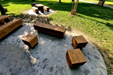 Tahta, büyük park bankının şekil bloğu granit doğal kaldırım taşı üzerinde metal bacaklı düzensiz kahverengi asfalt yaya bölgesi meşe ağacından prizma tek parça gövde, ızgara yerinden, oval
