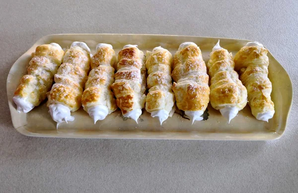 it tastes great from mom, cream rolls on a tray in a row next to each other sprinkled with powdered sugar. a must-have at any wedding or birthday party, pipe, tube