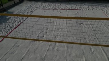 Beyaz kum plajı voleybol sahası. Ağlarla çevrili beyaz kumullar. Oyun alanının çizgileri mavi tekstil plastik kayışlardan yapılmıştır