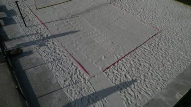 Beyaz kum plajı voleybol sahası. Ağlarla çevrili beyaz kumullar. Oyun alanının çizgileri mavi tekstil plastik kayışlardan yapılmıştır