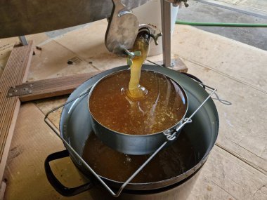 Arıcı arı kovanlarındaki bal miktarını ve kalitesini tahmin ediyor. Arılar akın ediyor, kovanlar ve kraliçeler tamamen meşgul. Bal makinesinden elek kapağına açılan kapaktan bal akar.