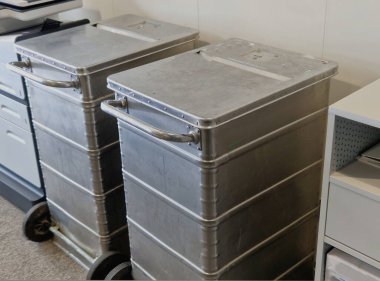 Ofisteki iş yerinde belge parçalama. Kağıtları şeritlere ayırıyor ve onları tekerlekli metal bir çöp kutusuna koyuyor. Cihaz yazıcının yanında, gümüş, çelik., 