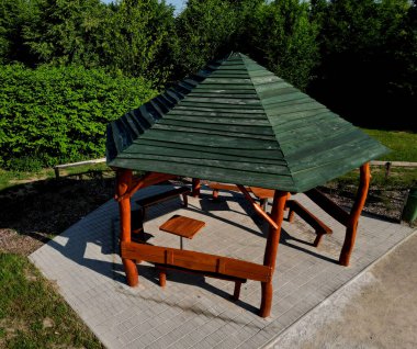 Çokgen pergola ve çevresi çitlerle çevrili. İçeride bir sürü yer var. Çatı, asfalt kiremitlerle kaplı piramitlerden oluşuyor. Doğal parkta, patikada, çakıllarda.