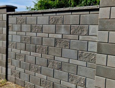 Düz bloklardan yapılmış beton duvar. Bahçenin yüksek bölücü ses duvarı. Duvarın altında boylamsal bir kanal var. Kanalizasyon boruları birbirine kenetlenmiş.