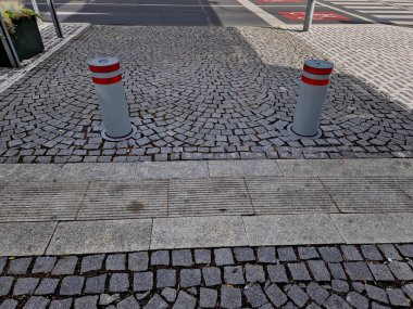 Tepesinde yarımküre olan kare silindirli otomatik bariyerler. Granit kaldırımlar otoparkta duruyor. Zincirleme çit, yayalar ve taşlı araçlar kolonisine karşı.