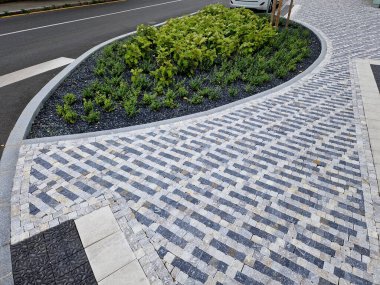 Adayı şeritler arasında bölen yaya geçidi. Yol işaretli kemerler, cadde boyunca kurumuş çiçeklerle dikilmiş. Bahçıvanlık. Lüks taş kaldırımlar ve kaldırımlar, daire