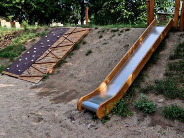 Çocuk parkında çift parlak paslanmaz çelik kaydırak. Palisades olarak kullanılan ahşap kütüklerle kaplı bir tepe. Güz parkı. Kayalık bir yamaca benziyor. Palisade, palissade, yamaç, tepe, teras.