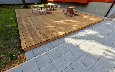 Meydandaki ağaçların altındaki kaldırımda sallanan sandalye. Parktaki tek bir kişi için tropikal ahşaptan yapılmış ahşap sandalyeler. Kahverengi kalaslar, çatallar, çelik çerçeveler ve çam ağacından yapılmışlar.