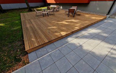 Meydandaki ağaçların altındaki kaldırımda sallanan sandalye. Parktaki tek bir kişi için tropikal ahşaptan yapılmış ahşap sandalyeler. Kahverengi kalaslar, çatallar, çelik çerçeveler ve çam ağacından yapılmışlar.