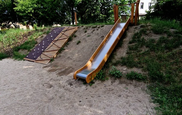 遊び場の二重光沢のあるステンレス製のスライド 柵として使われている木の丸太が並ぶ丘 秋の日公園 岩の斜面 パリザード パリサード テラス 上に似ています — ストック写真