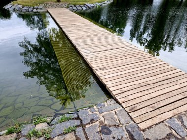 Korkuluksuz park yeri. Hemen yanında suyun altında bir güvenlik ağı var. Yüzeyin altında. Böylece köprüyü genişletir ve derinliğe düşme olasılığını azaltır.