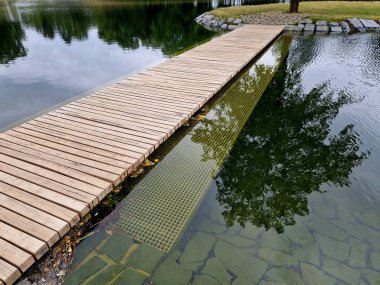 Korkuluksuz park yeri. Hemen yanında suyun altında bir güvenlik ağı var. Yüzeyin altında. Böylece köprüyü genişletir ve derinliğe düşme olasılığını azaltır.