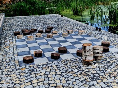 Rıhtımdaki parkta dinlenme terası. dama tahtası desenindeki kiremitler ve bloklar dama taşlarını temsil ediyor. Taslak masa oyunu. Büyük ölçekli. granit döşeme.