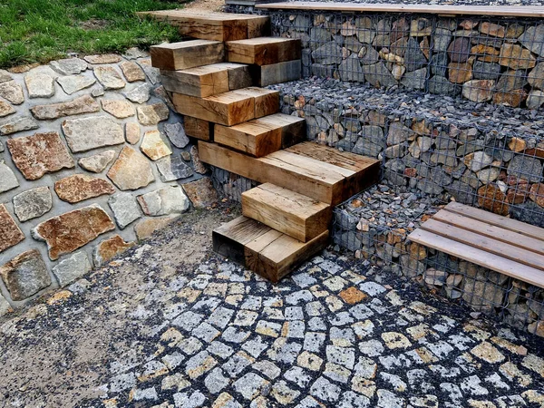 how to solve the steep entrance to the water on the dam. oak beams stacked and screwed together in a chaotic direction on top of each other. gabion slope go down the stairs
