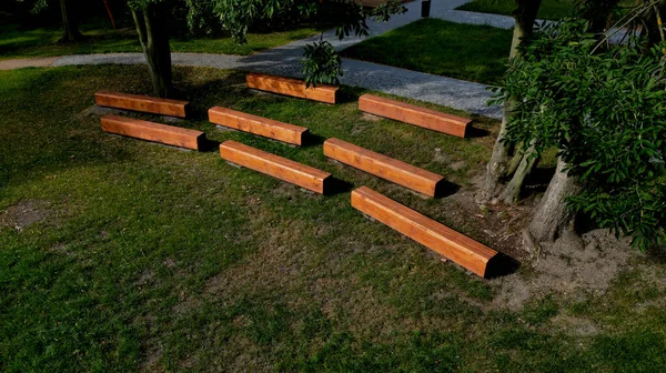 theater amphitheater for audience seating. the wooden prisms are on a concrete foundation. foot trims made of one piece of wood stained brown, ptanque  playground, bowling, threshing