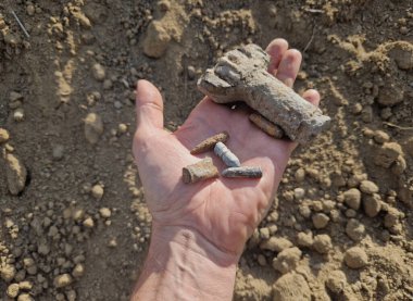Eski atış poligonlarının ve savaş alanlarının havai fişek temizliği. Detektörler, yerleşim yerlerinin yakınındaki toprakta bir sürü metal parçası ve mermi olduğunu gösteriyor. Paslı savaş zamanı parçasını tutan adam.