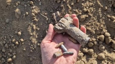 Eski atış poligonlarının ve savaş alanlarının havai fişek temizliği. Detektörler, yerleşim yerlerinin yakınındaki toprakta bir sürü metal parçası ve mermi olduğunu gösteriyor. Paslı savaş zamanı parçasını tutan adam.
