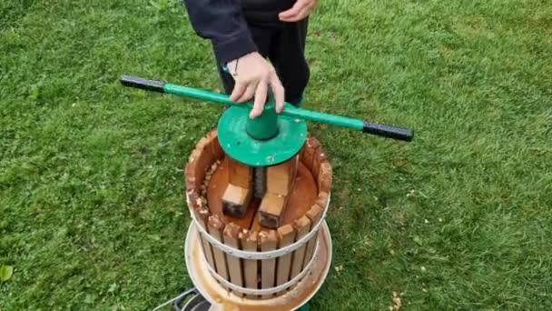 手押しで押すりんごから自家製サイダージュースを作るネジの子供たちと一緒にハンドルサイダーを回すのを助けるふるいにかけてパルプを堆肥にスローされます — ストック動画