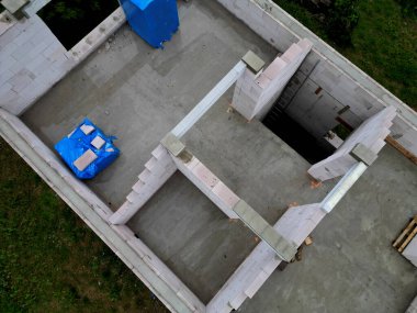 Aile evinin inşaat alanının manzarası. Paletlerde tuğlalar ve çıplak duvarlar. Çatı kirişi. Kirişler yerleştirildi, binanın içindeki tuğlaların kalitesi, gelişimi, finansmanı