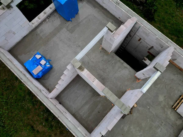 Aile evinin inşaat alanının manzarası. Paletlerde tuğlalar ve çıplak duvarlar. Çatı kirişi. Kirişler yerleştirildi, binanın içindeki tuğlaların kalitesi, gelişimi, finansmanı