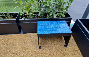 Çiçek saksılarına çalılar dikmek ve onları palet kamyonuyla belirlenmiş yere taşımak. Konteynırlarda bitki yetiştiriyorlar. Otoparktaki gri dikdörtgen teneke kutular.