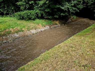 Çamurlu su, gergin nehir yatağında hızla ilerler. Boğulmak kolaydır. Düşenler, köprünün altındaki derinliklere süpürülür. Alandan gelen su akışı aynı zamanda üst toprağı da süpürür.
