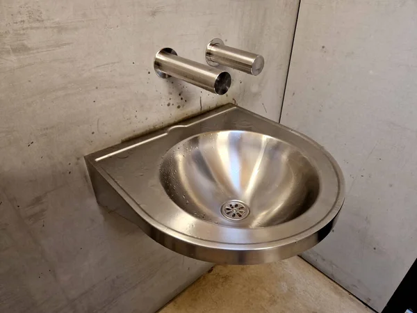stainless steel sink with automatic battery reminds the interior of an airplane. however, it is on the bike path by the public toilets. truck, pub, football, camp, prison, prisson, gas station