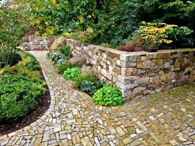 Taş duvardaki eklem yerinden, paslanmaz çelik bir çarşaf boyunca akan su, uzun ömürlü ve eğreltiotu dolu bir gölete akar. Parktaki ve bahçedeki güzel katlanmış duvarlar şirketimiz tarafından yapılacak.