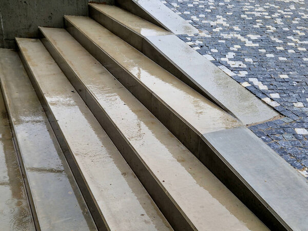 wet concrete staircase is new and smooth. seating stairs for students and people in the park. lawn benches and beds with perennials in combination with building elements