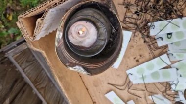 Kovandaki akarlara karşı tıbbi ürün uygulaması. Aktif bileşeniyle tutuşturulmuş kağıt parçası damlıyor ve kuluçkaya yatmış arı larvalarıyla çerçeveler arasında dumanla yanmasına izin veriliyor.