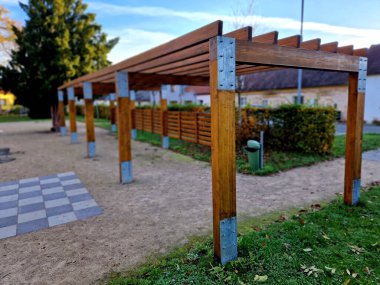 terrace with wooden pergola and plexiglass roof. vines are straining, crawling under the beams. garden or park. sitting with dry wall wine region. restaurant countryside france, truss