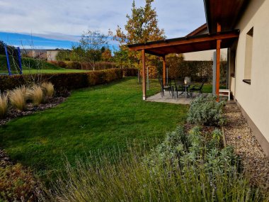 Süslü otlarla dolu çiçek tarhı sonbahar güneşinde kuru yapraklar sarı yaprak demetleri parlar. Arka plandaki çalılıklarda ve boynuz direğinin yaşam alanında. Kahverengi yapraklar çimenlik, kaldırım taşı, kumtaşı