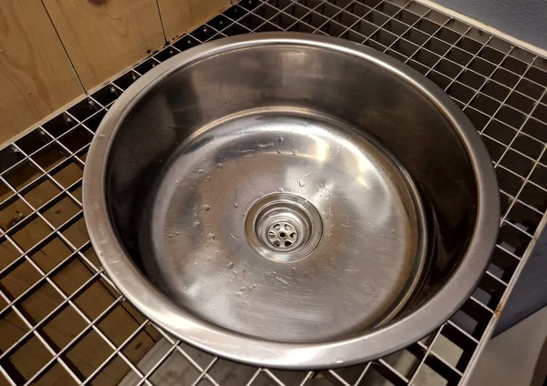 the stainless steel sink embedded in  grid resembles the interior of an airplane. however, it is on the bike path by the public toilets. truck, pub, football, camp, prison, prison, gas station, circle