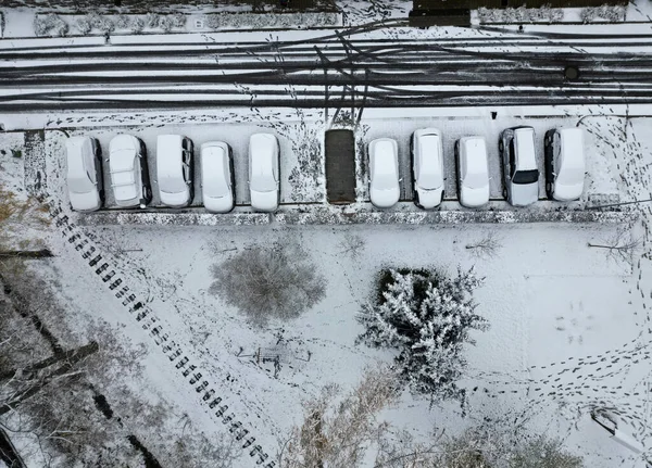 the parked car is outlined in snow. someone stole one, you can see the traces around. surveillance and guarding with gps and police drone operator. cleaning and maintenance of road. track