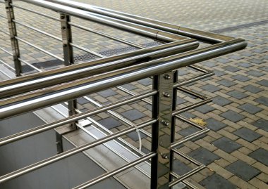 staircase and wide pedestrian bridge with perforated metal floor. galvanized sheet metal with circular holes. white railings like on a ship in the arch. handrail made of polished stainless steel pipe.