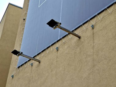 advertising tarpaulin installed by cable into the metal galvanized eye on the facade of the house. Mobile advertising solutions, easily replaceable content for outdoor use on apartment buildings