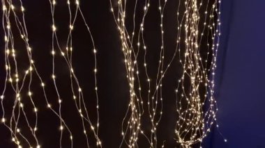 Koyu mavi arka plandaki ışık zincirleri gece yıldızlı bir gökyüzünü andırıyor. Noel için aydınlatılmış süslemelerle sergi standı, dal, daire, huş ağacı kabuğu, beyaz, 