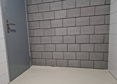 gray concrete blocks of the walls of a purpose-built warehouse with a door to a garage of austere design clipart