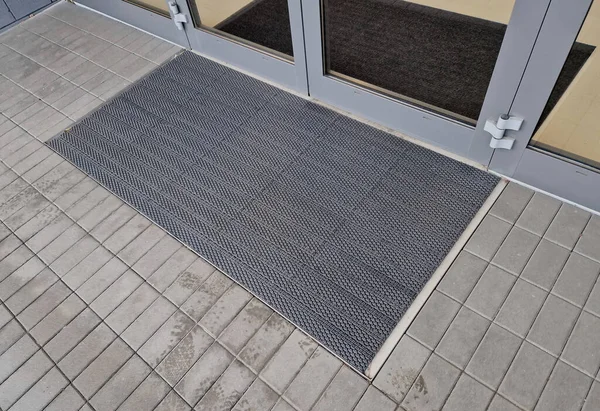 industrial mat cleaning zones at the entrance to the building. black plastic-metal mat in the shape of an arch or half-circle lies on the limestone mosaic tiles