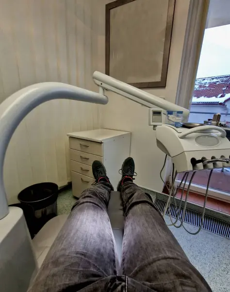 dental examination. a man sits in a crib and looks down at his feet. unpleasant tooth treatment by a dentist. nice dental chair missing dentists, renting an expensive workplace with client patients