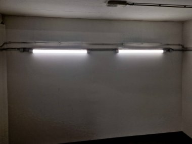 Sapının altında sarı ışıklı bir LED şerit var. Gizli lamba bir adamın elini gösteriyor. Merdivenin beton tarafı, istinat duvarları olan gece, koridor.